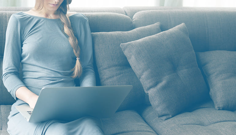 mujer de baja laboral por accidente de tráfico con el ordenador en el sofa de su casa